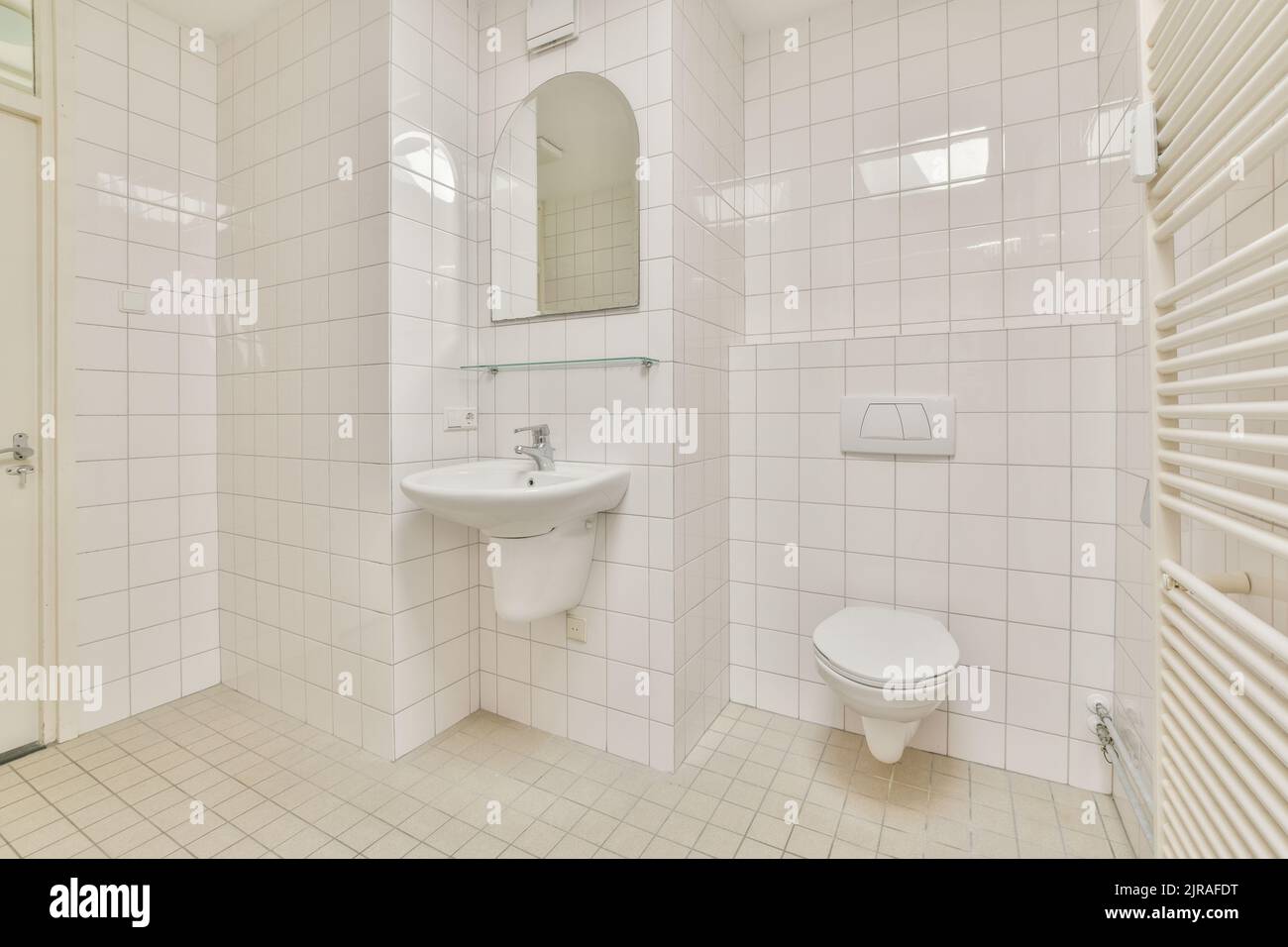 Wall hung toilet and small sink in corner in lavatory room with beige