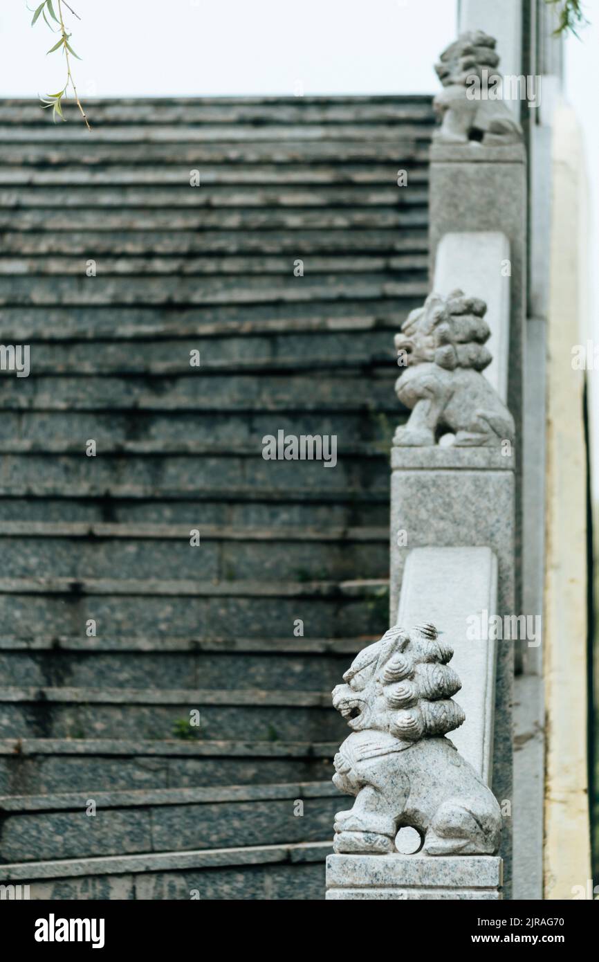 Craved A vertical shot of stairs with Komainu craved stones on the Handrail ...
