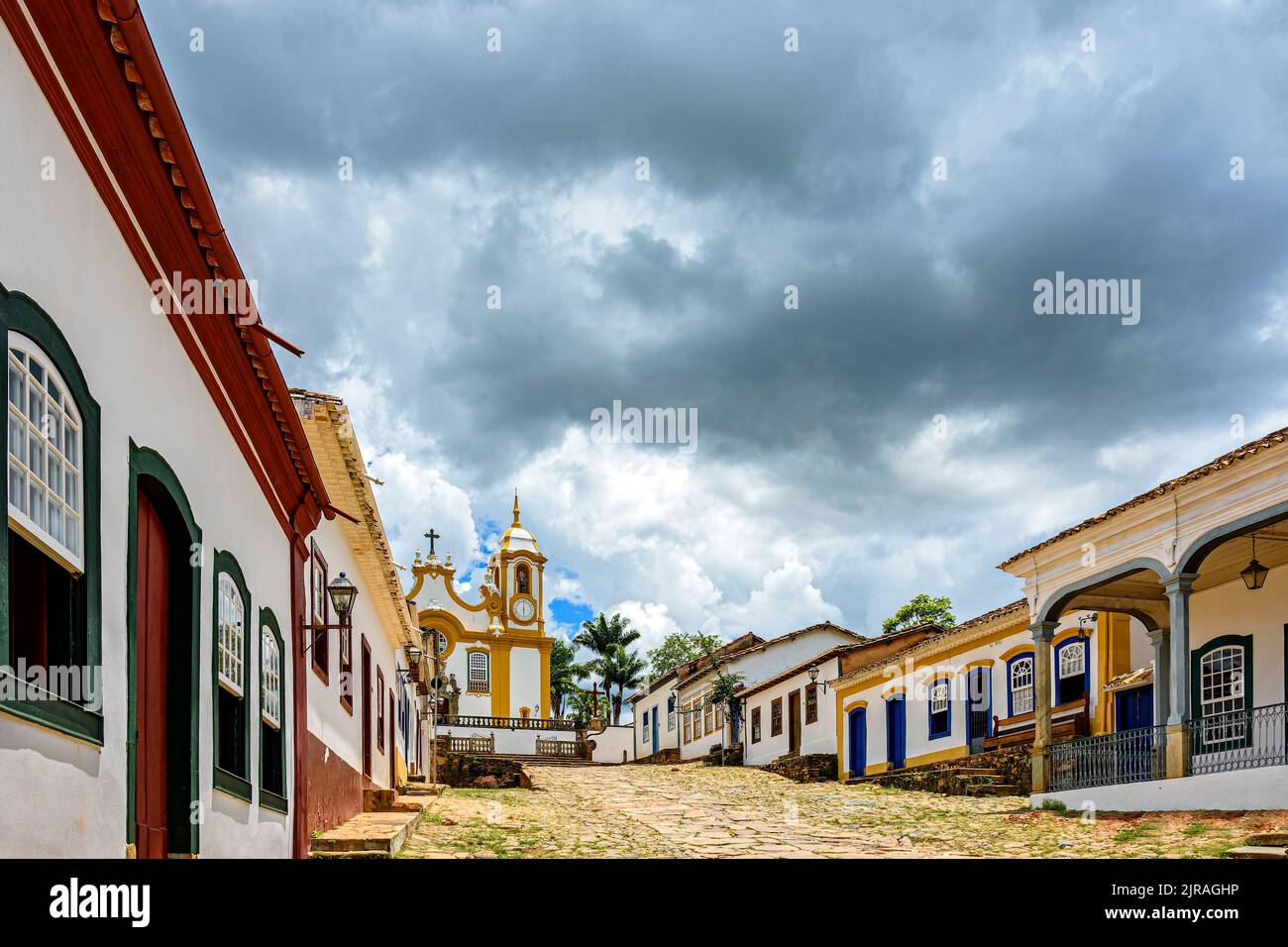 Street and old colonial style houses in the historic city of Tiradentes in Minas Gerais with a baroque church in the background Stock Photo