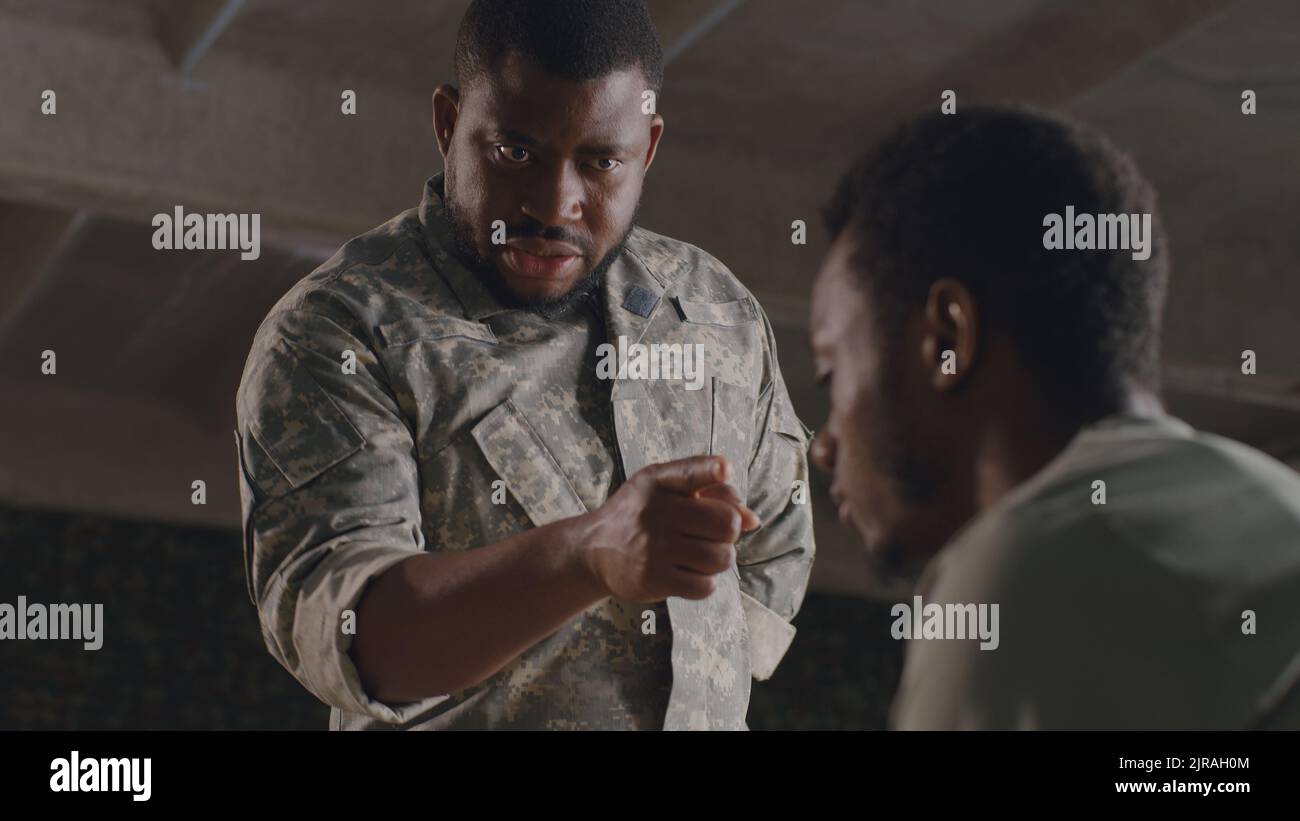 From below black military man gesticulating and scolding male soldier on military base Stock Photo
