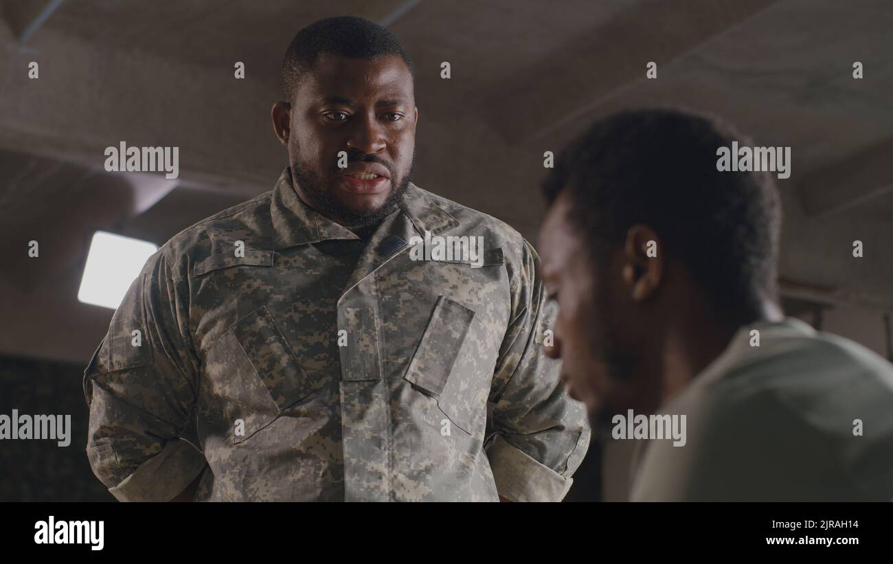 From below black military man gesticulating and scolding male soldier on military base Stock Photo
