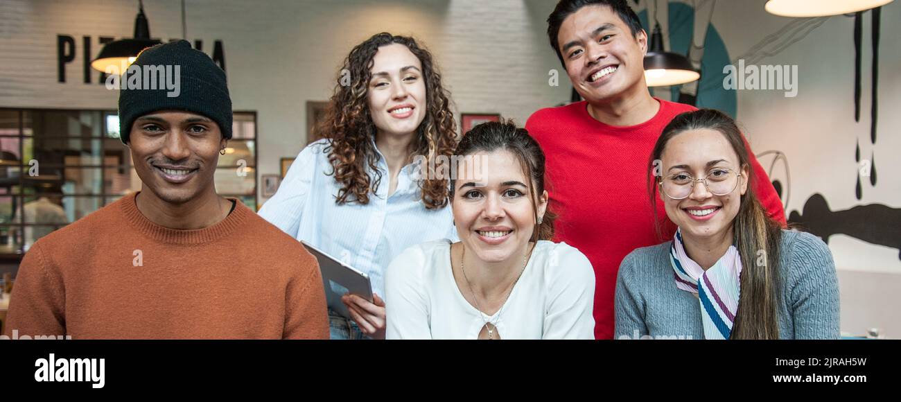 Horizontal banner or header with smiling multiethnic coworkers looking at camera making team picture in multifunctional room of the pizza restaurant f Stock Photo