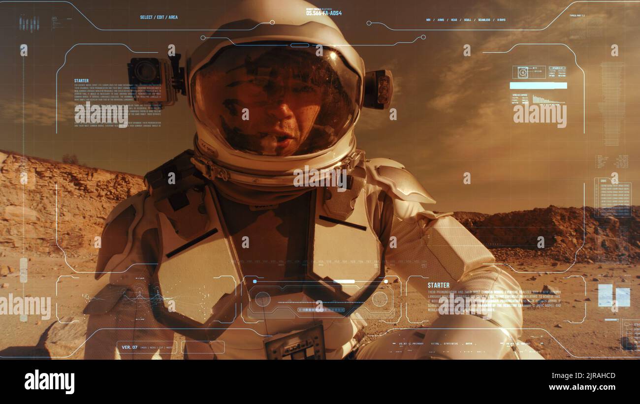 Man in spacesuit turning on camera and pointing at arid terrain while recording video message from surface of Mars Stock Photo