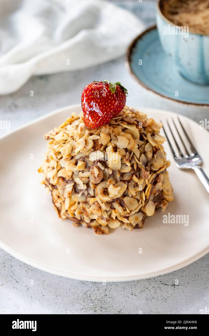 Hazelnut, strawberry and chocolate cake on gray background. Fruit and cream cake covered with chocolate on the outside. close up Stock Photo