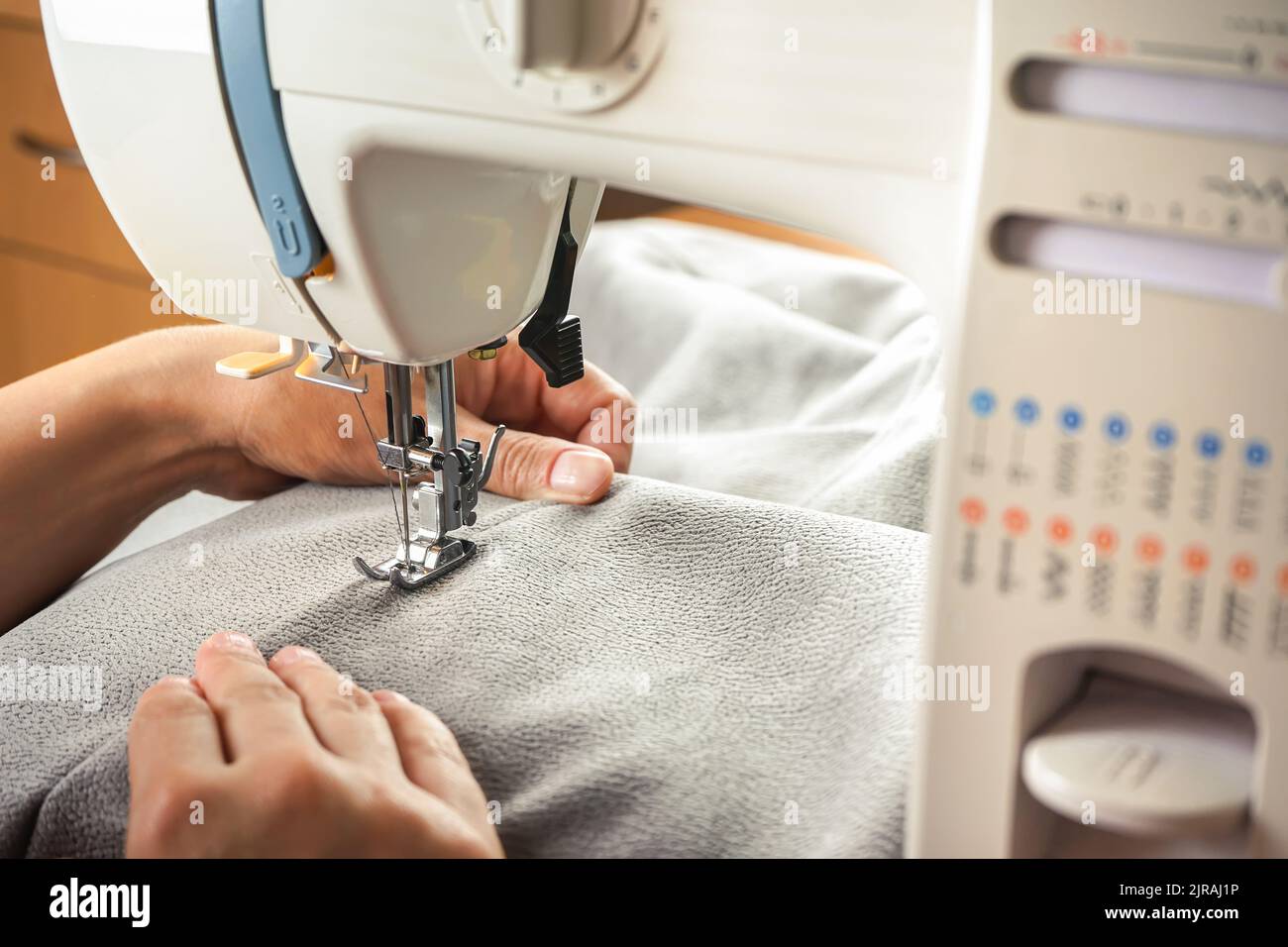 Seamstress female hands holding and stitching gray textile fabric on ...