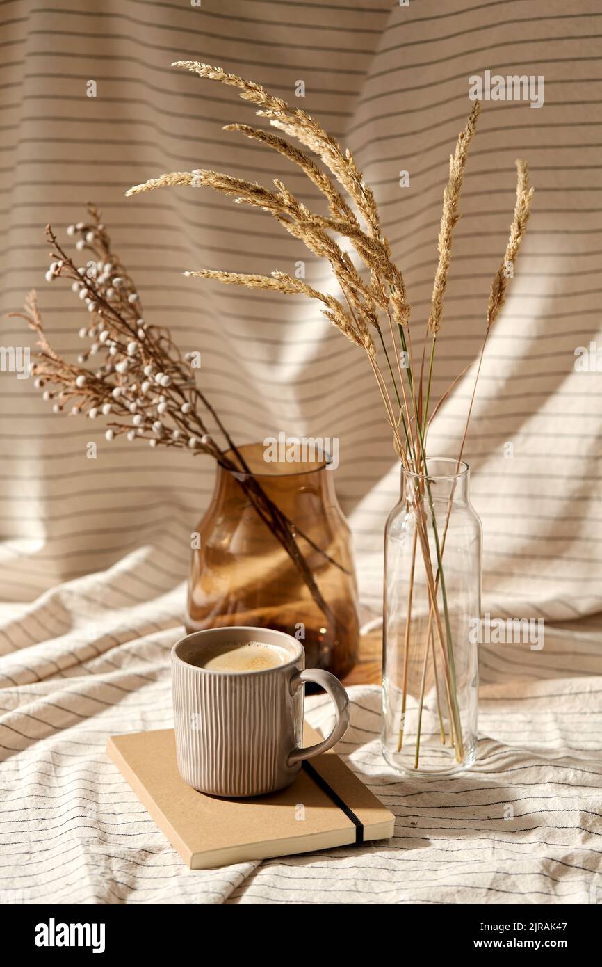 cup of coffee, diary and dried flowers in vases Stock Photo Alamy