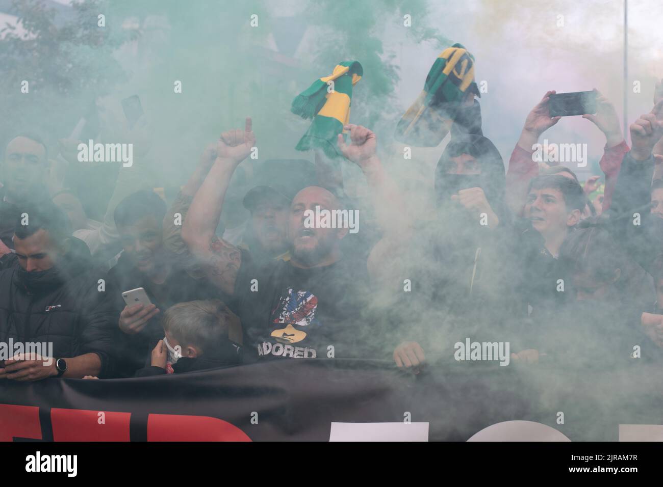 Protest march at Manchester United against Glazer owners. Green and gold smoke flares. Match against Liverpool. Stock Photo