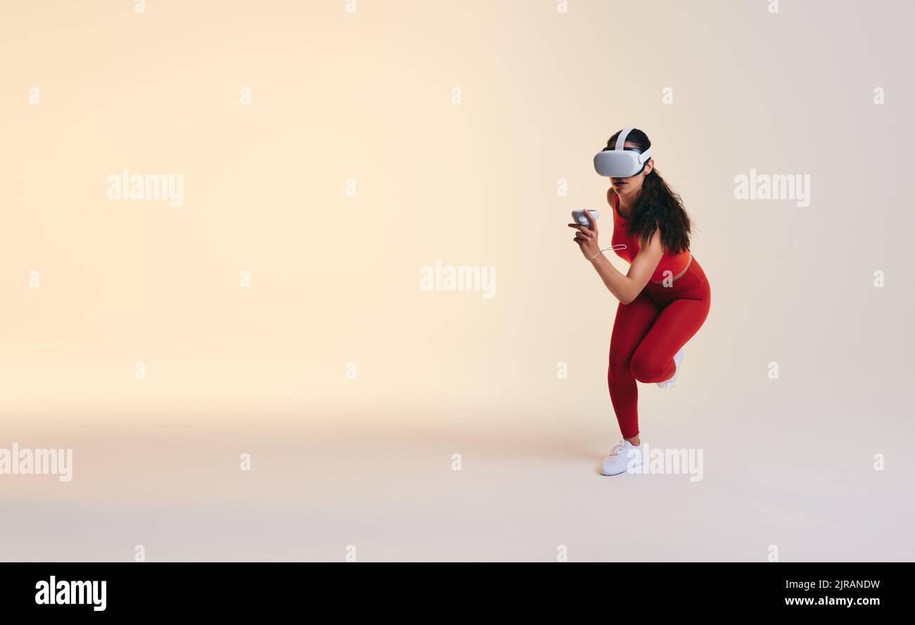 Young sportswoman woman running in virtual reality. Athletic young woman working out using 3D technology. Active young woman wearing a virtual reality Stock Photo