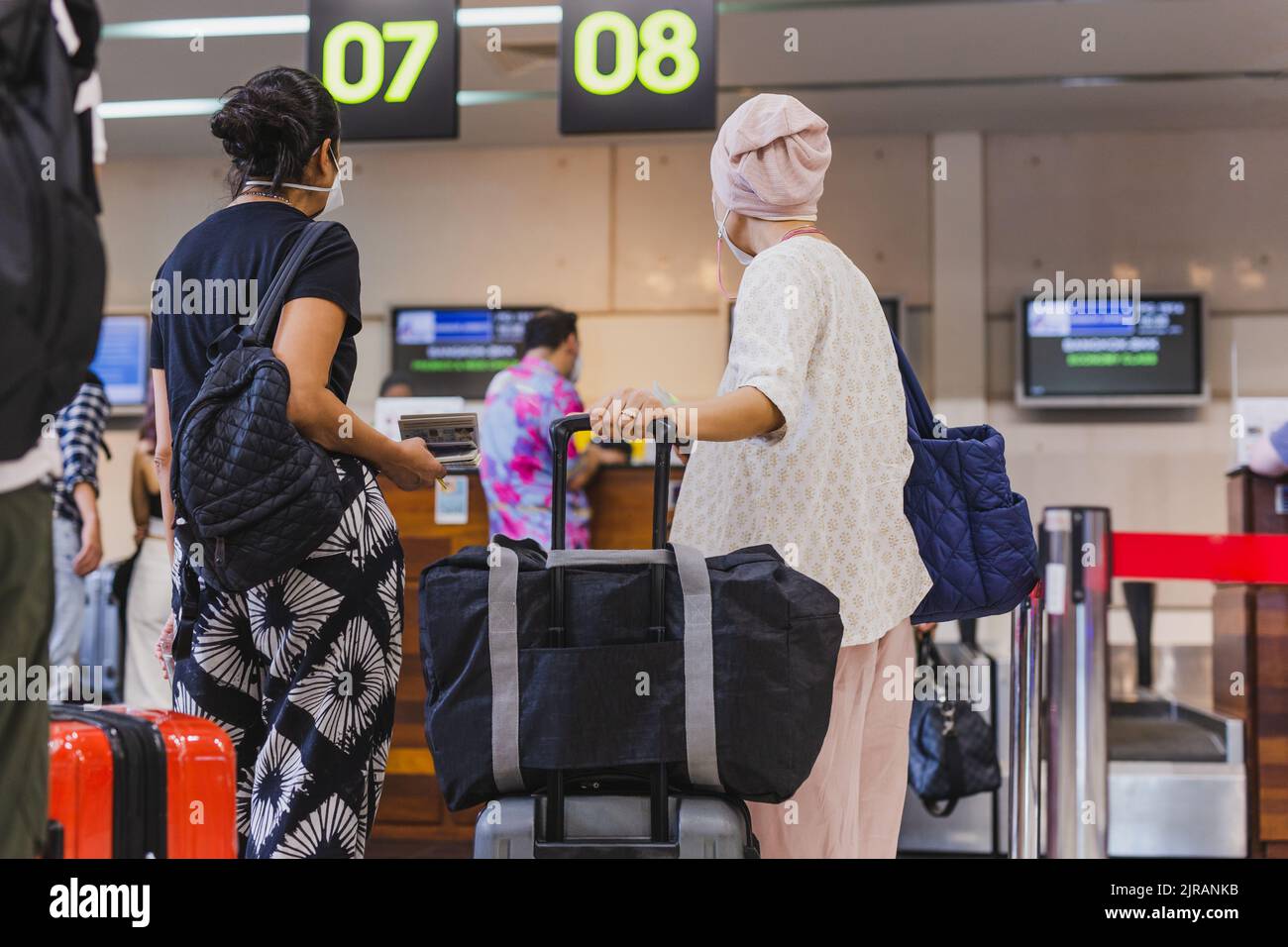 Two woman passengers with face mask check in at the airport Stock Photo ...
