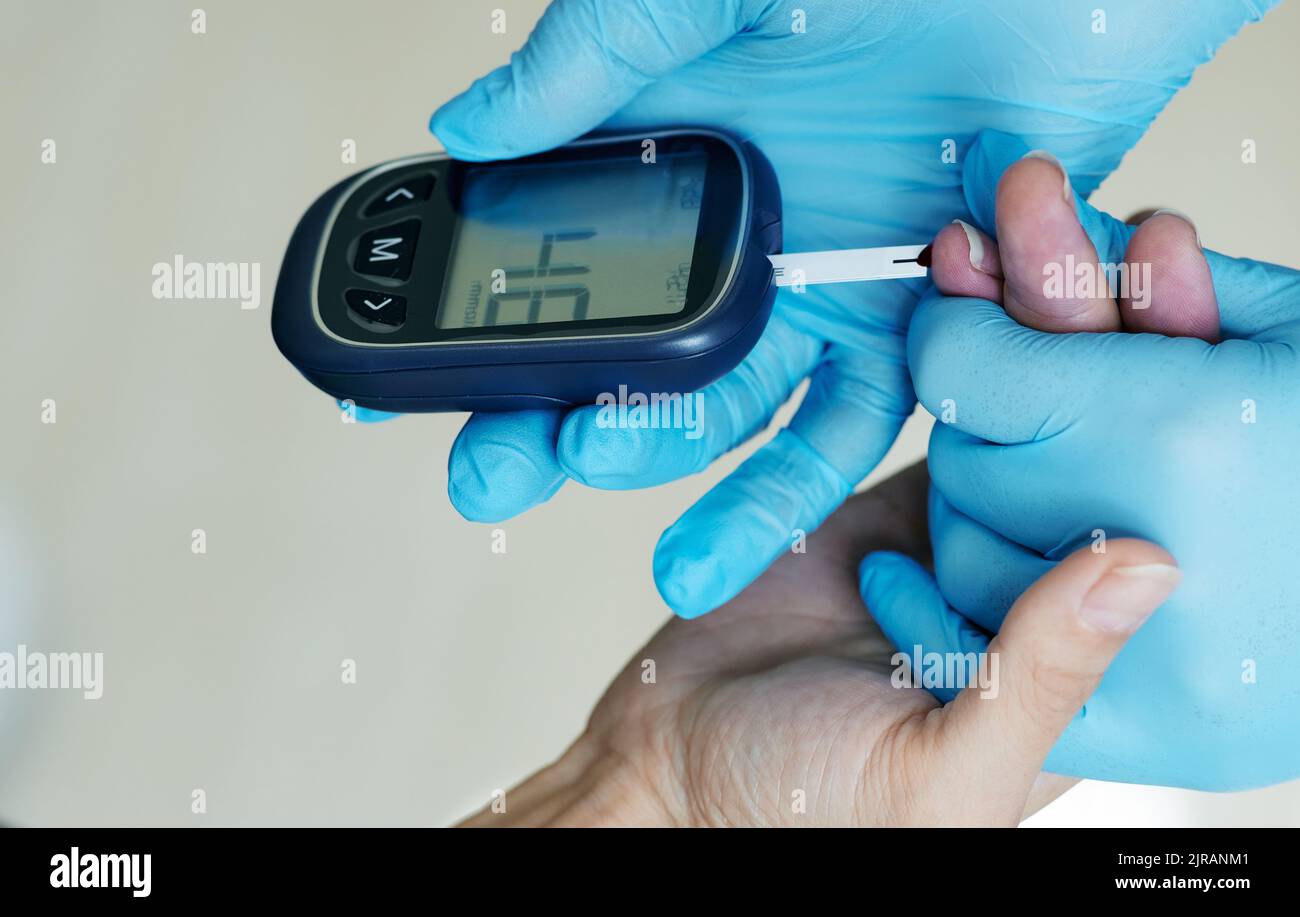 Medical worker checking blood glucose level of diabetic patient using closeup