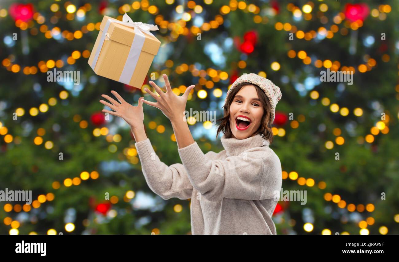 young woman in winter hat catching gift box Stock Photo