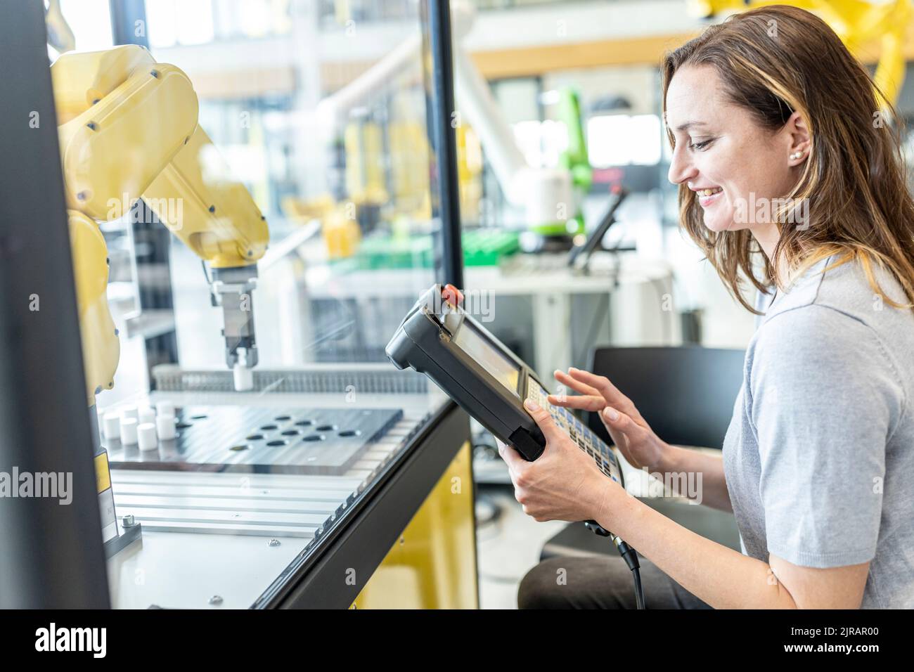 Woman in factory using control of industrial robot Stock Photo
