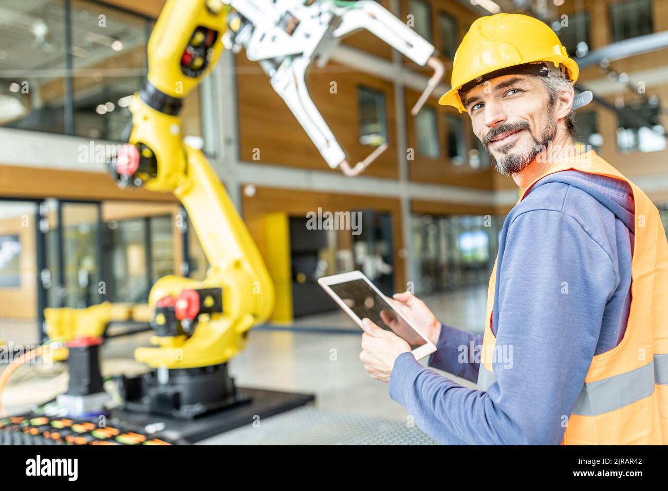 Confident skilled worker controlling robot arm with digital tablet Stock Photo
