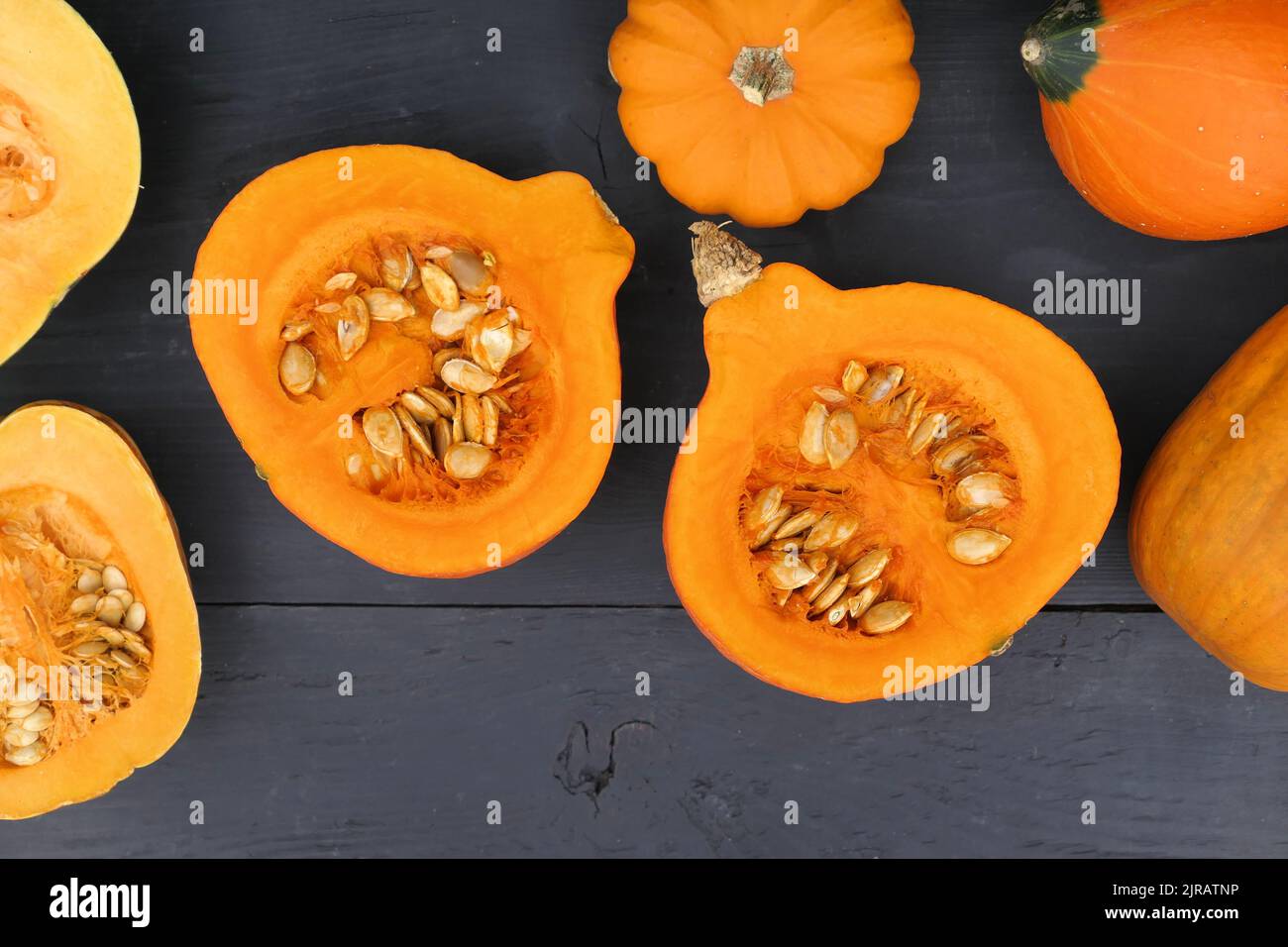 Cut pumpkins on black background. Top view. Pumpkin pulp and seeds food. Stock Photo