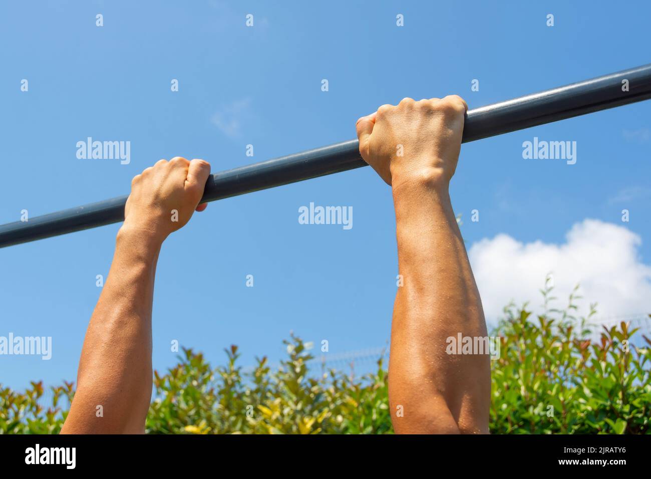 Hands hold on to the horizontal bar on the street, outdoor workout area