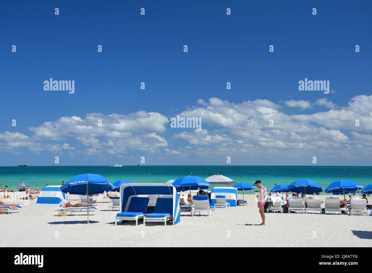 Miami Beach, USA - March 18, 2017 : Tourists on beach sunbeds and umbrellas in South Beach, Miami Beach by Atlantic Ocean. Stock Photo