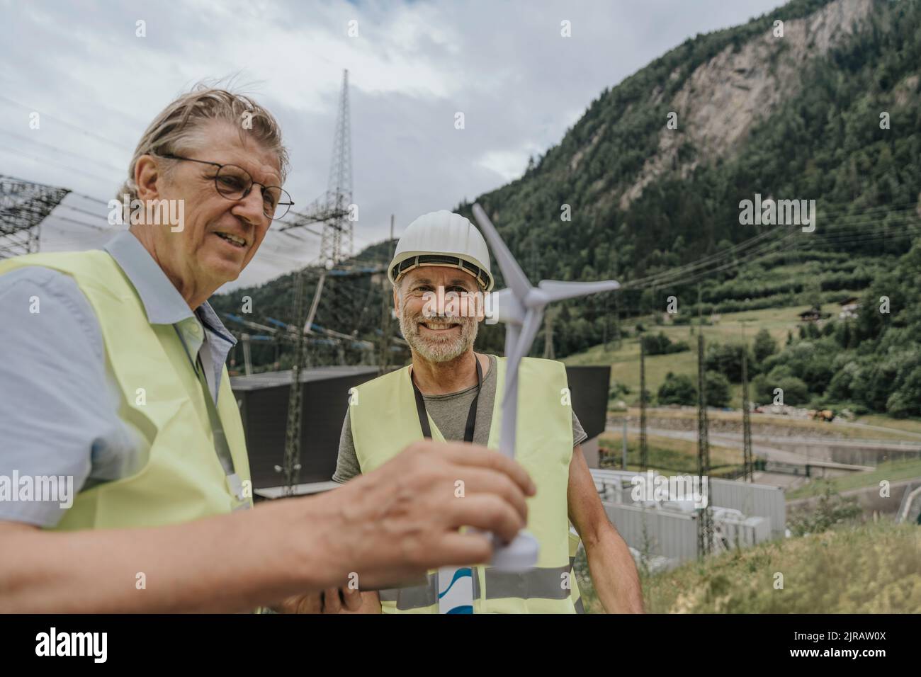 Smiling engineer discussing over wind turbine model Stock Photo