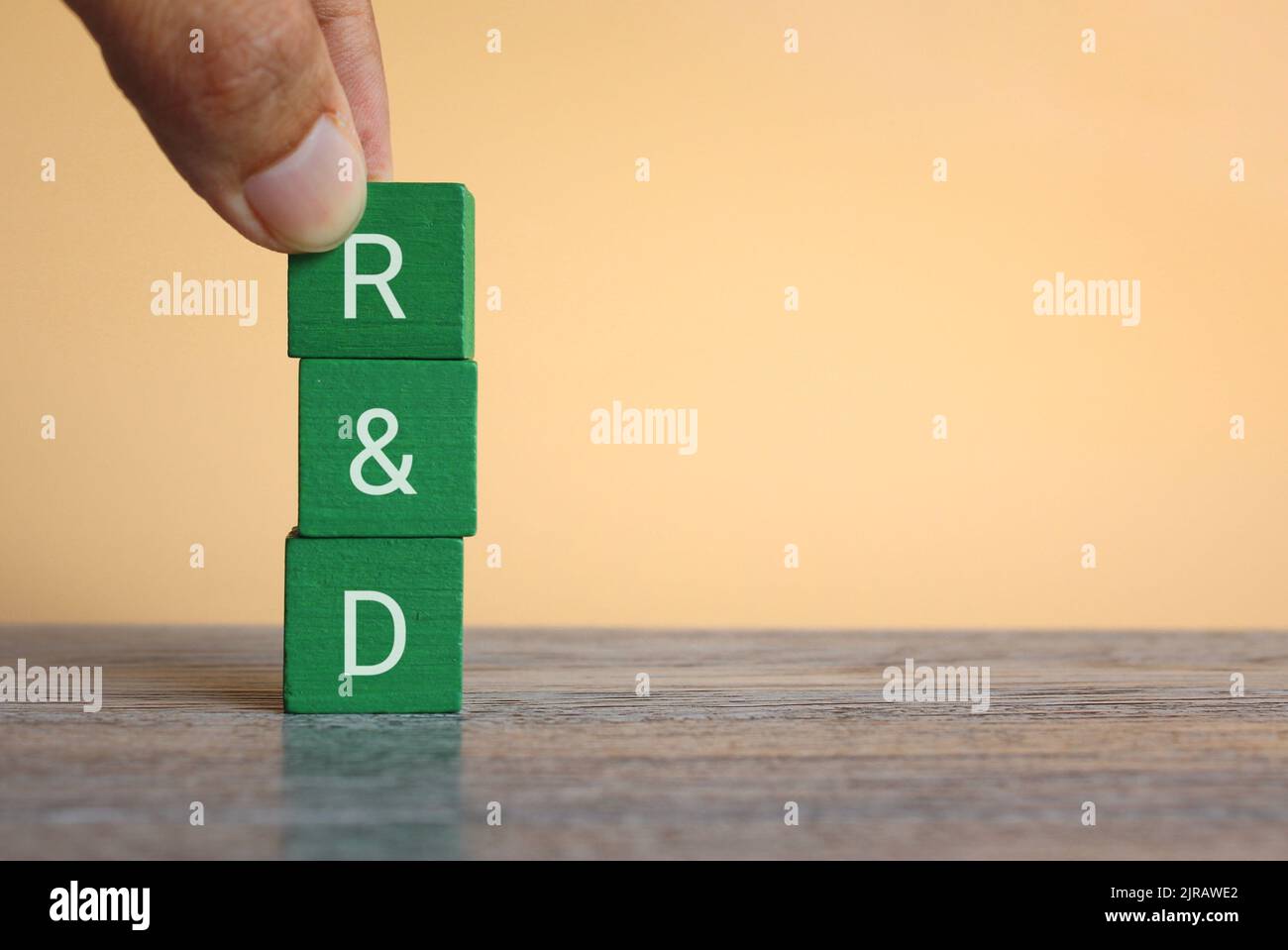 Hand holding wooden cubes with text R and D on table with copy space Stock Photo