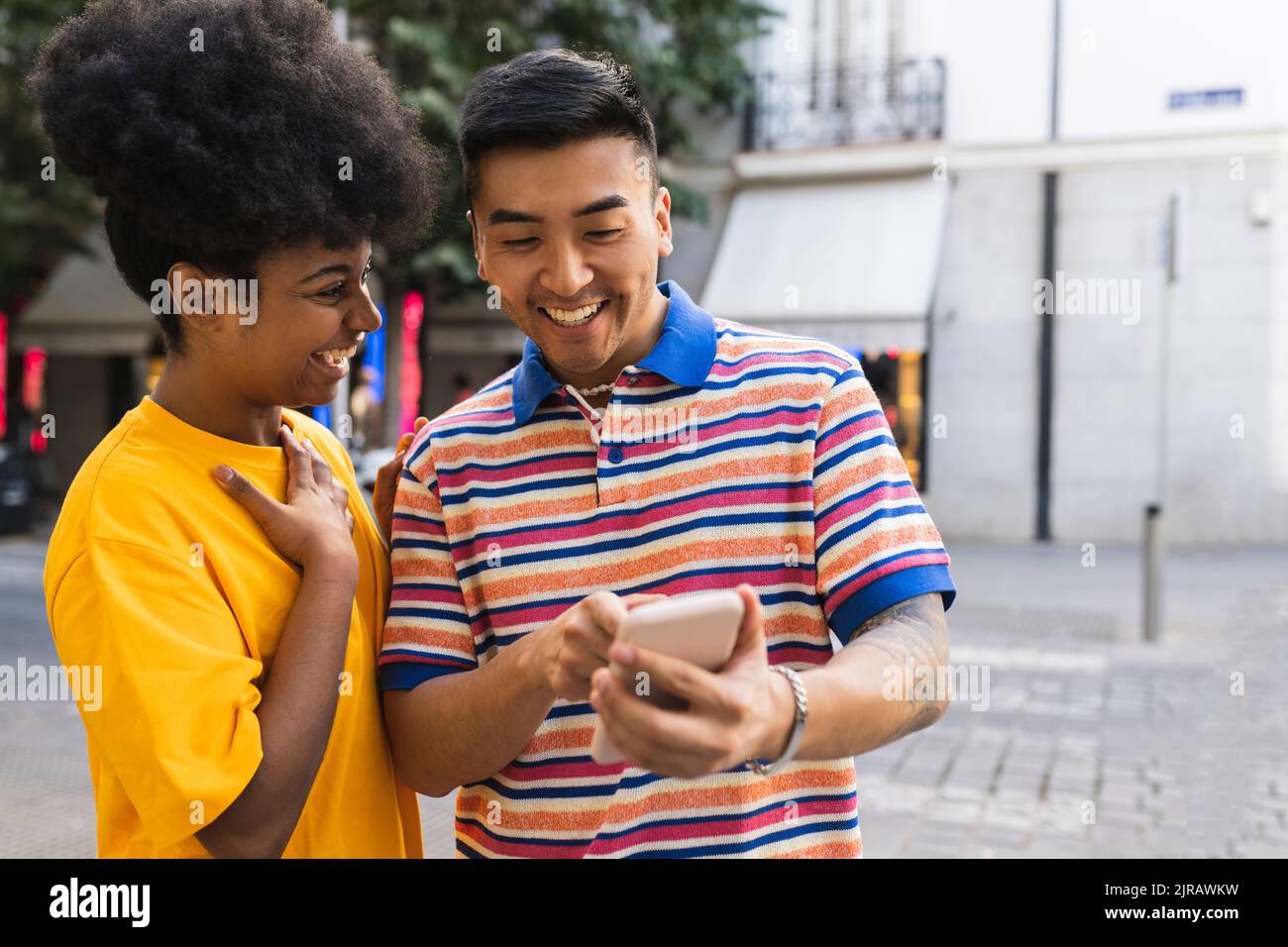 Cheerful young woman looking at man using smart phone Stock Photo