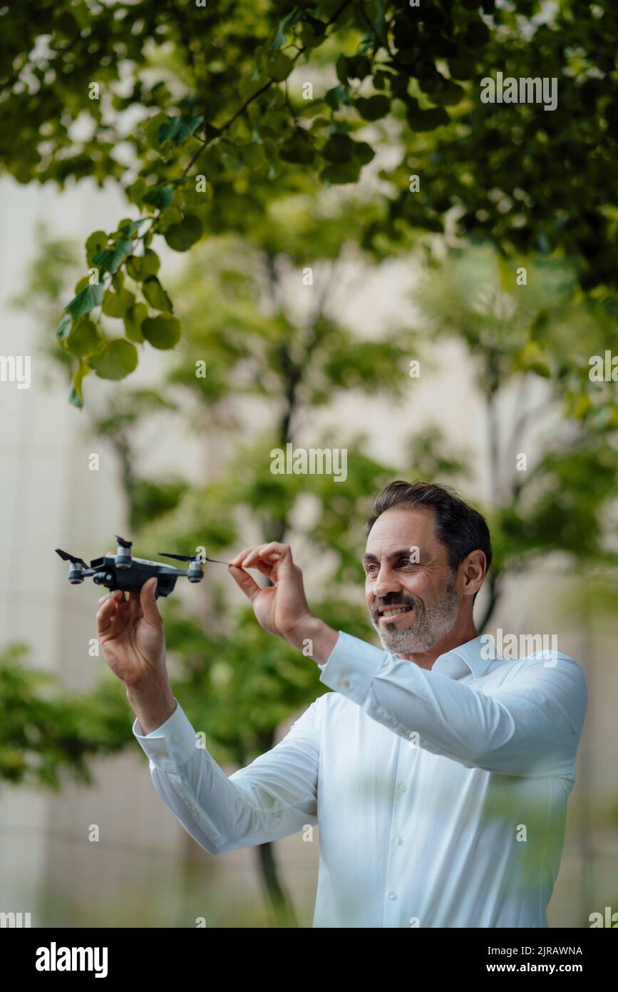 Smiling mature businessman analyzing drone Stock Photo