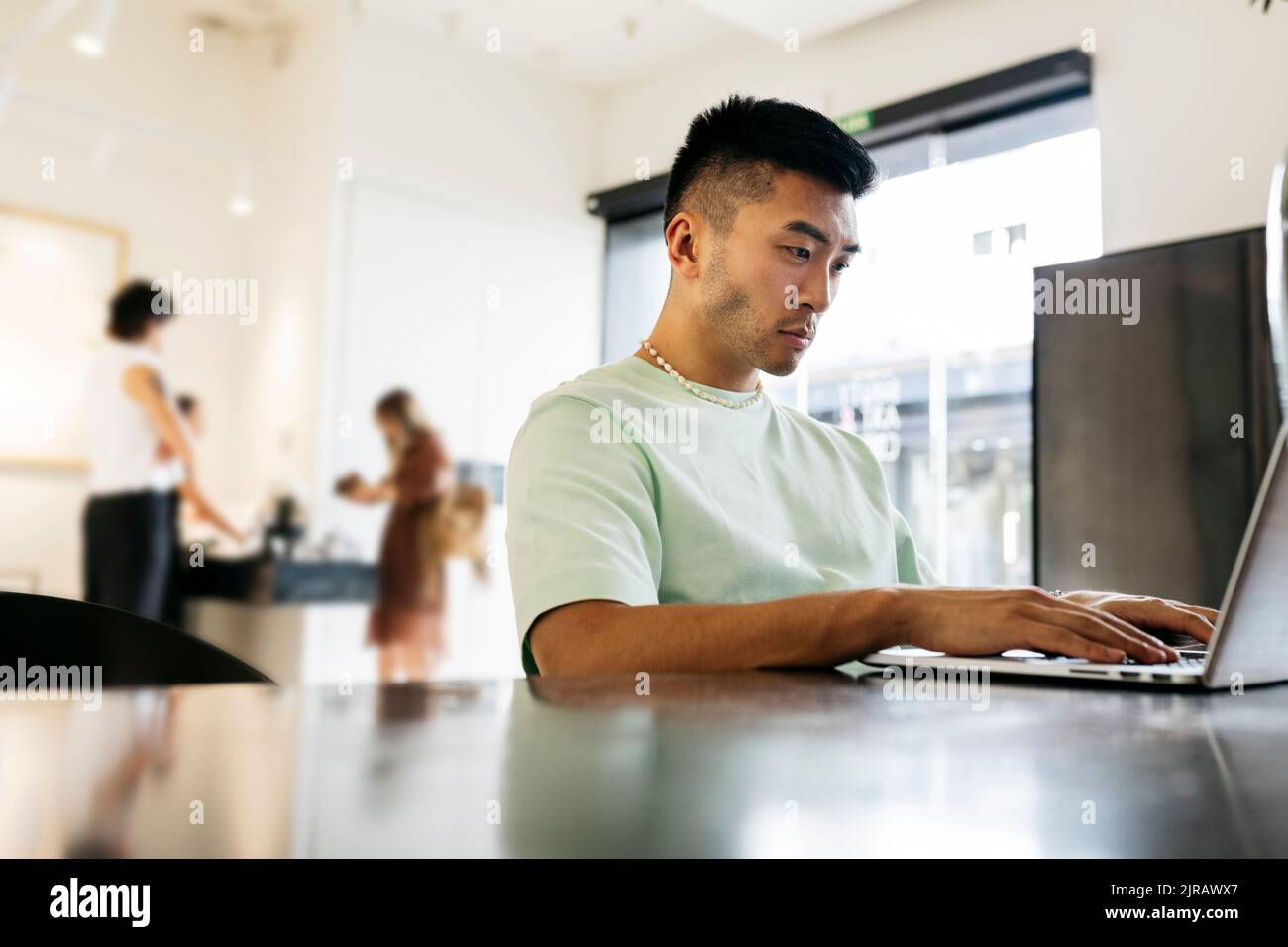 Young man using laptop sitting at table in cafe Stock Photo