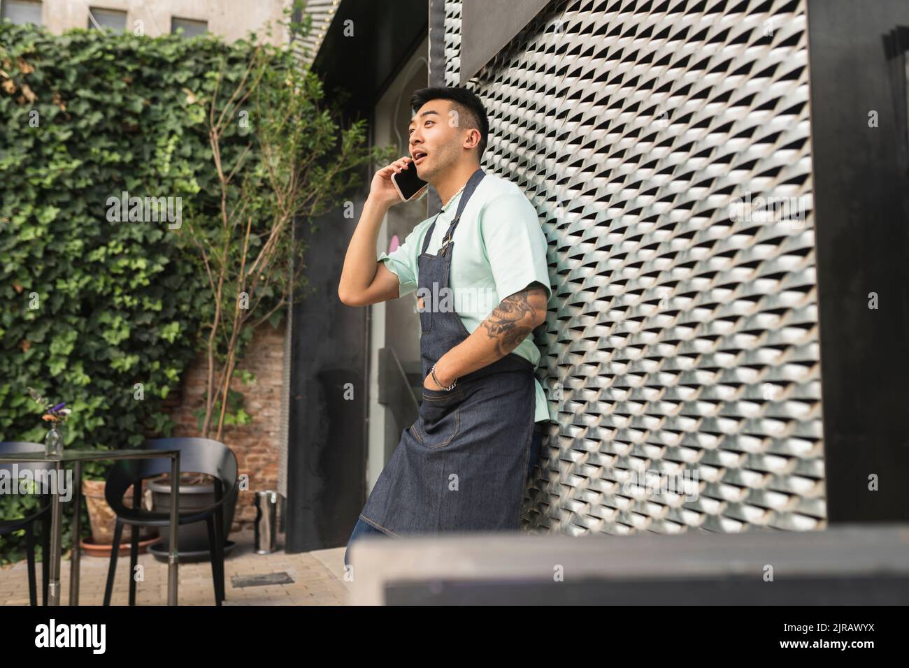 Surprised man talking through mobile phone leaning on wall Stock Photo