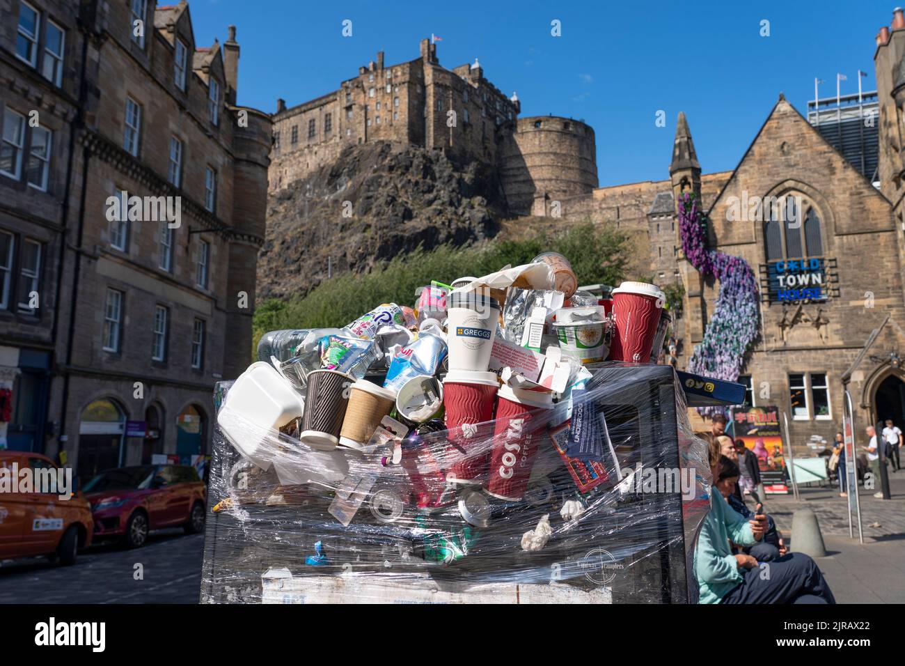 Edinburgh, Scotland, UK. 23rd  August 2022. Rubbish is seen piled on the streets of Edinburgh city centre on day six of a 12 day strike by city refuse collectors. Pic; A full but sealed bin with Edinburgh Castle to rear. Iain Masterton/Alamy Live News Stock Photo