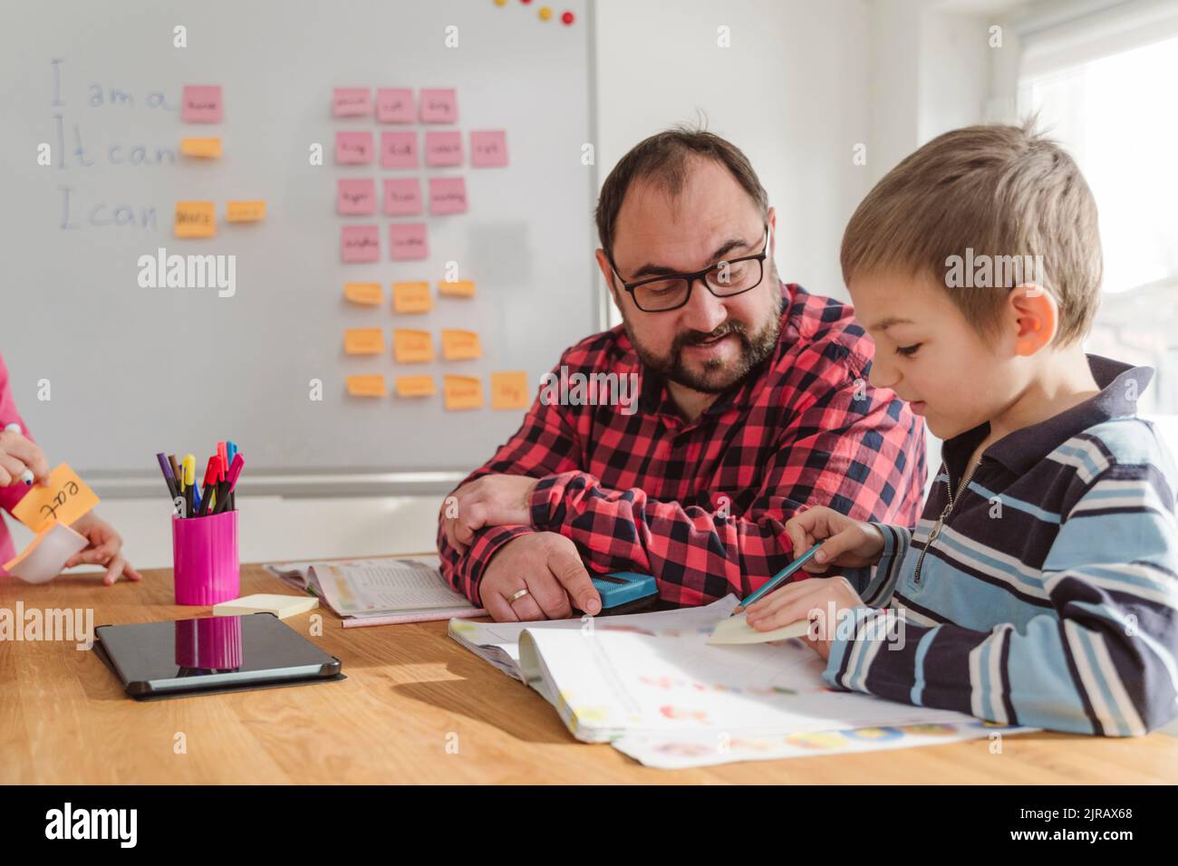 Boy with book learning English language from teacher at home Stock Photo