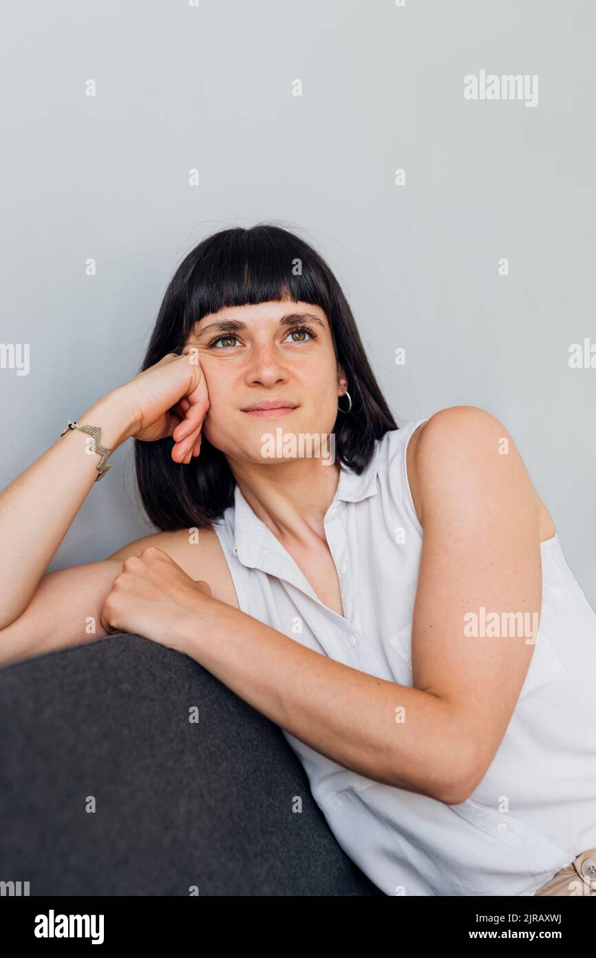 Contemplative woman sitting on couch at home Stock Photo - Alamy