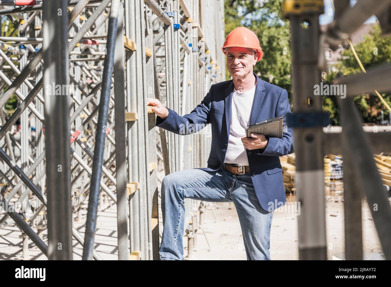 Smiling engineer with tablet PC standing by scaffolding Stock Photo