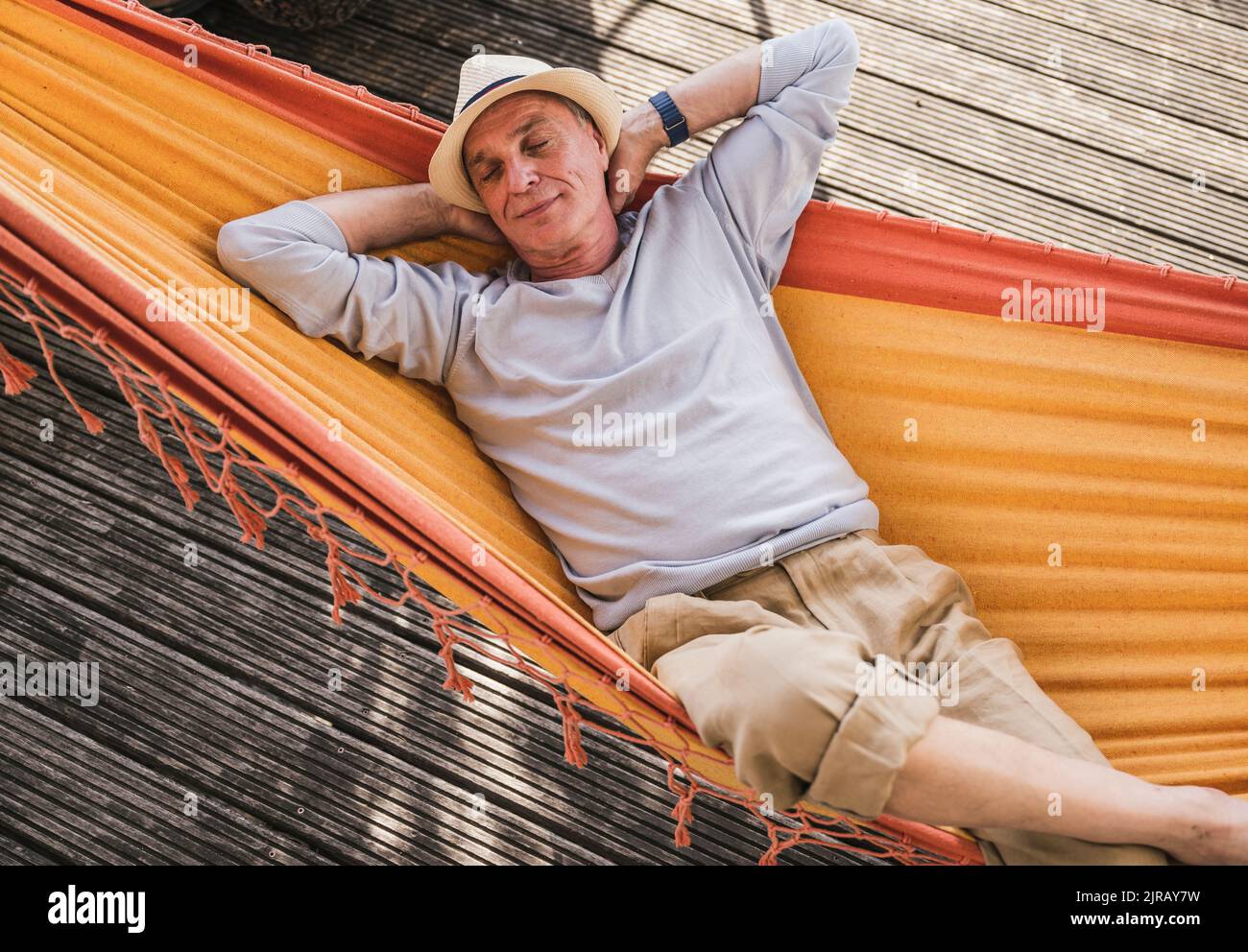 Man with hands behind head sleeping in hammock Stock Photo