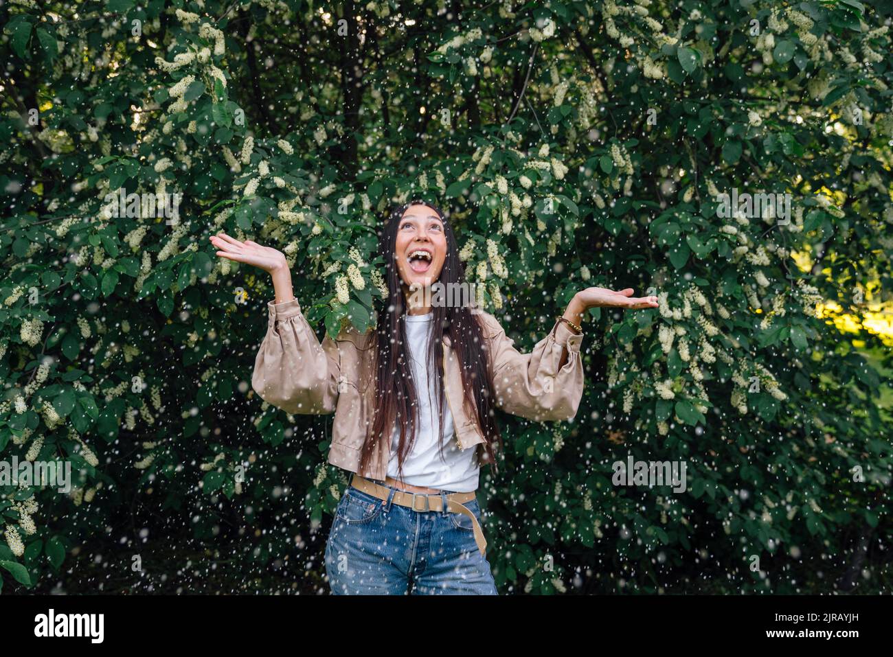 Excited woman standing under blooming tree Stock Photo