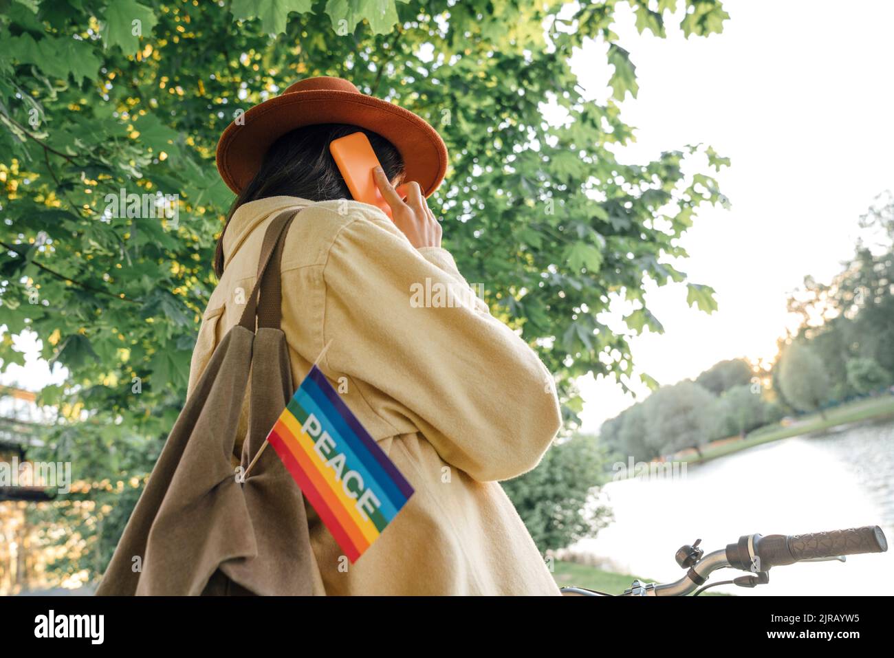 Woman talking on smart phone with peace flag hanging from bag Stock Photo