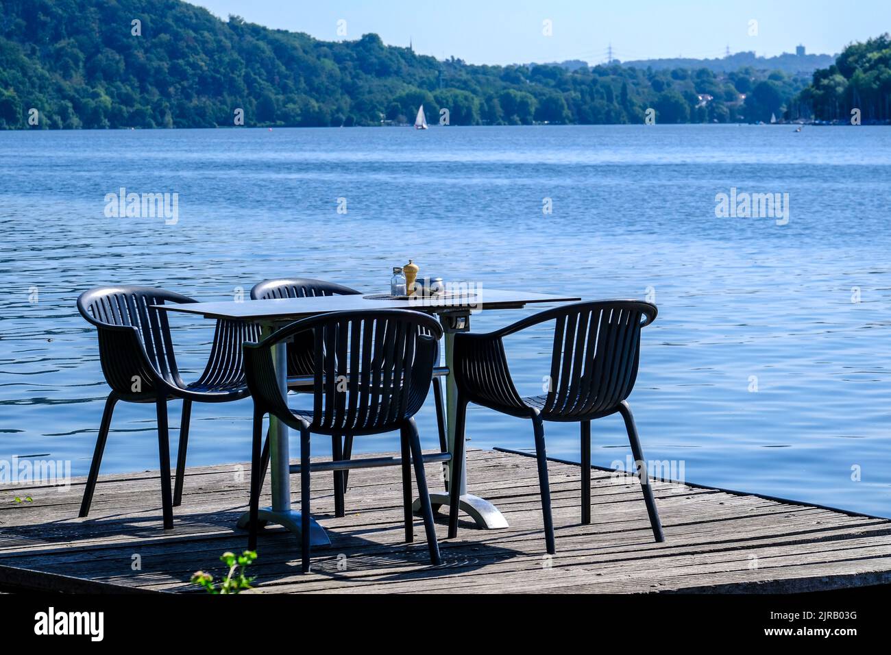 DEU, Deutschland, Nordrhein-Westfalen, Ruhrgebiet, Essen, 23.08.2022: ein leerer Tisch am Essener Baldeneysee auf einem Bootssteeg vor dem Ausflugslok Stock Photo