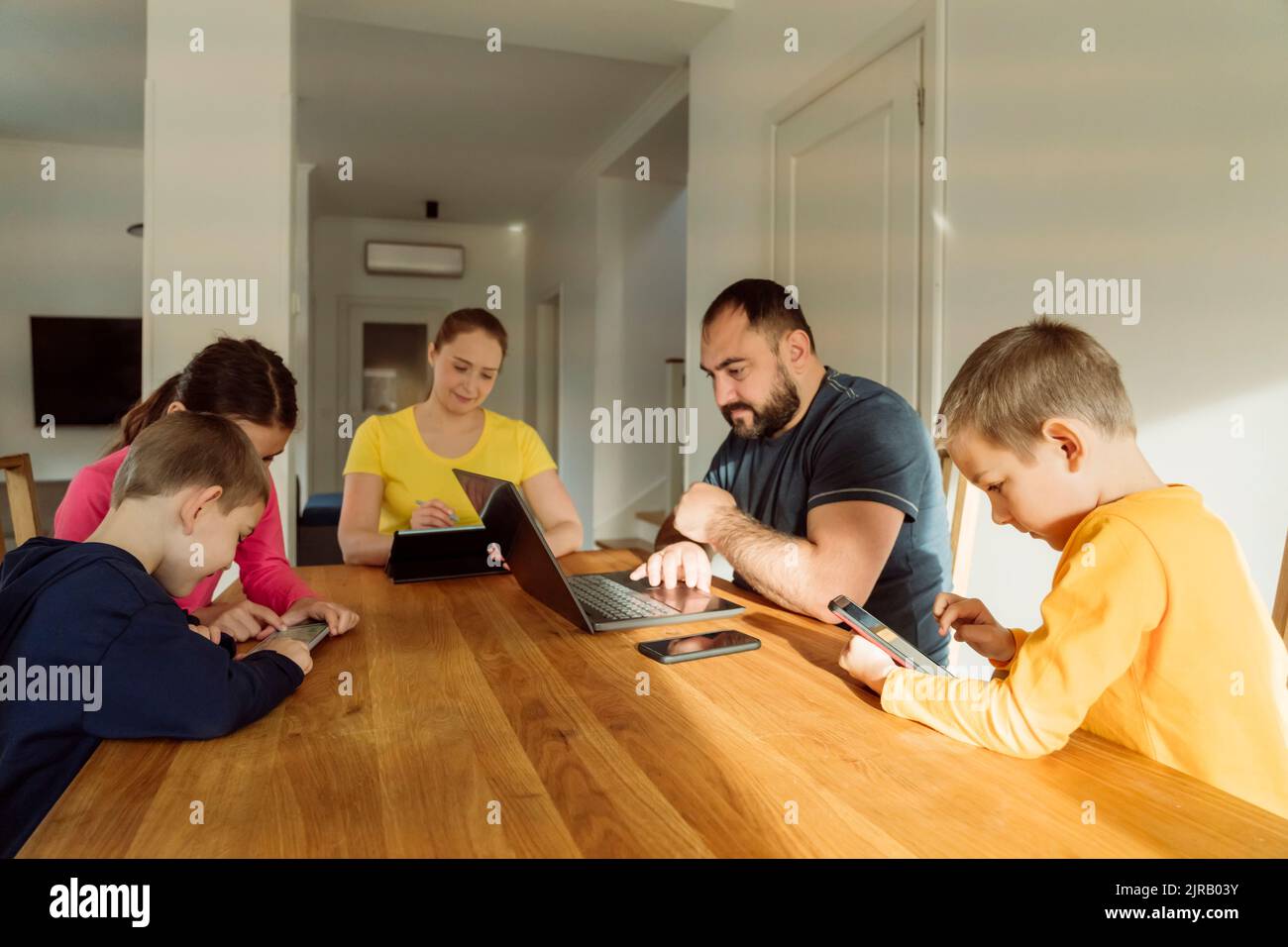 Family using wireless technologies on table at home Stock Photo
