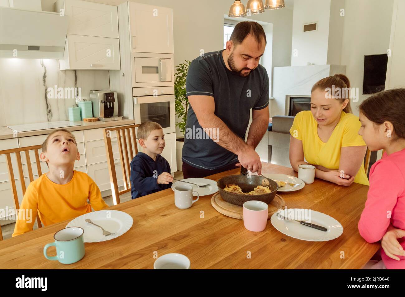 Father serving breakfast to woman and children at home Stock Photo