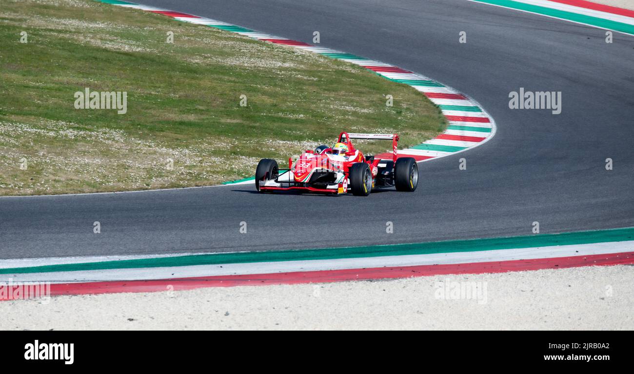 Asphalt racetrack turn and curbs with red car racing on track. Mugello, Italy, march 25 2022. 24 Hours series Stock Photo