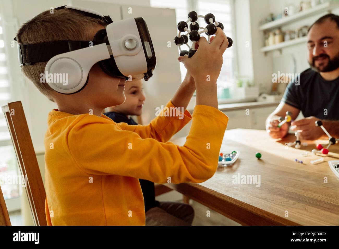 Boy wearing virtual reality goggles examining molecules at home Stock