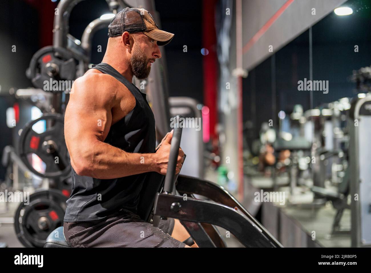 Bodybuilder using exercise machine in gym Stock Photo