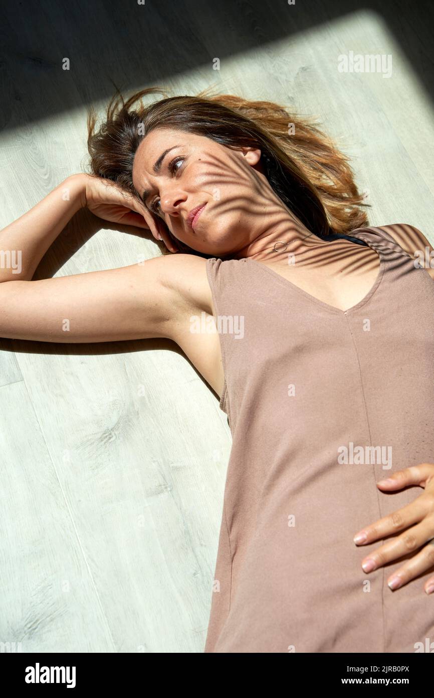 Woman lying down on floor in sunlight Stock Photo