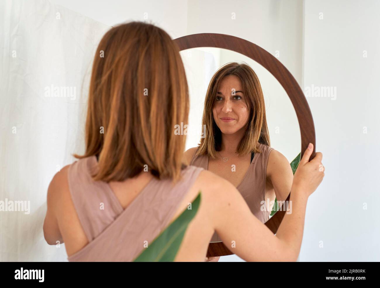 Smiling woman looking in mirror at home Stock Photo