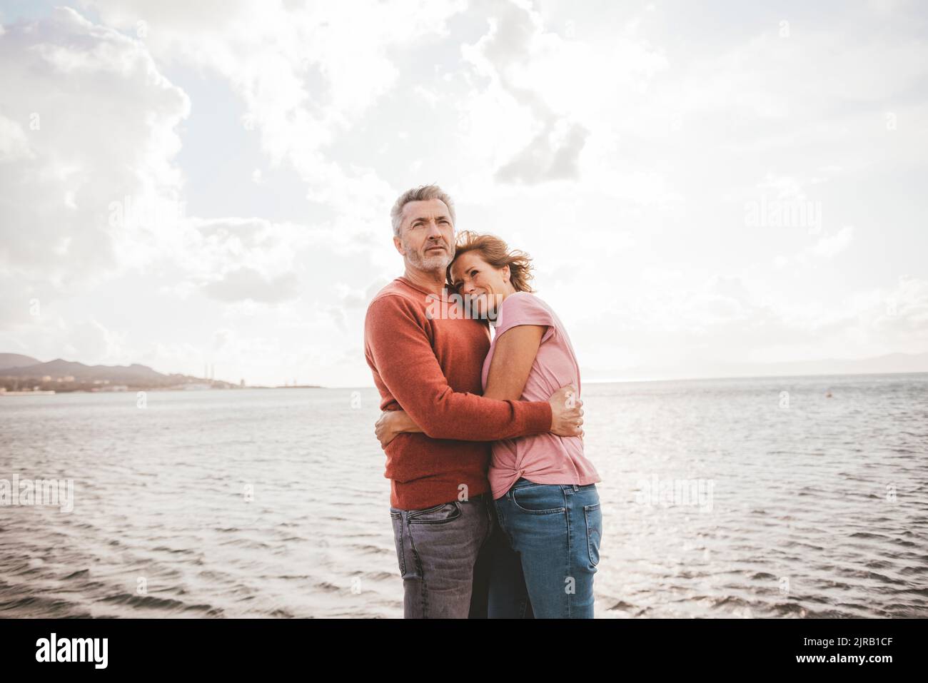 Smiling woman hugging man in front of sea at beach Stock Photo - Alamy