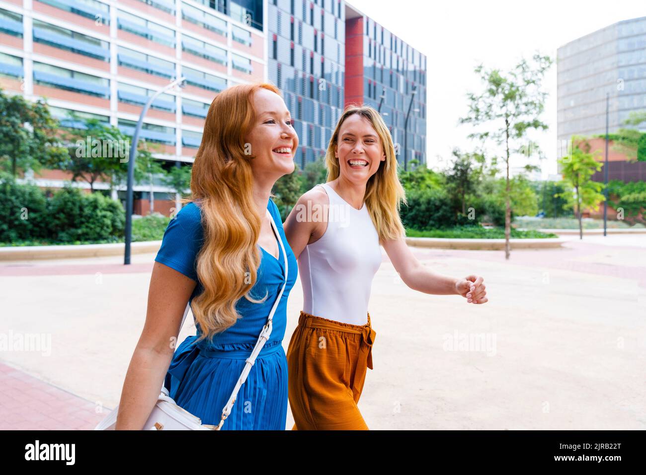 Happy friends walking together on footpath in city Stock Photo