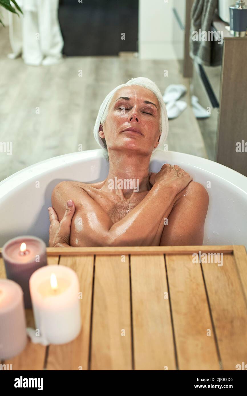 Mature woman taking bath and relaxing in bathroom Stock Photo