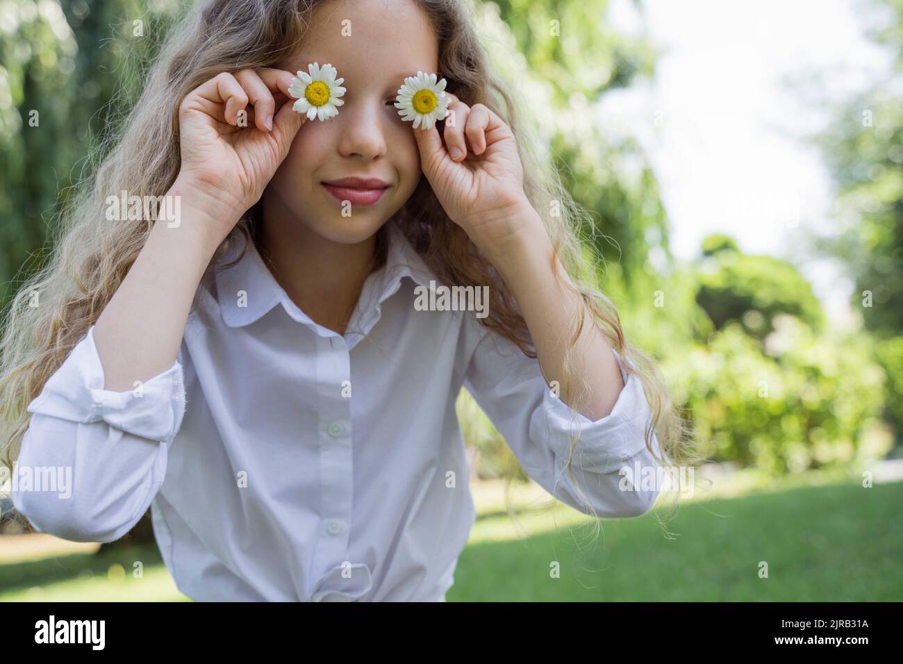 Girl covering eyes with chamomile flowers Stock Photo - Alamy