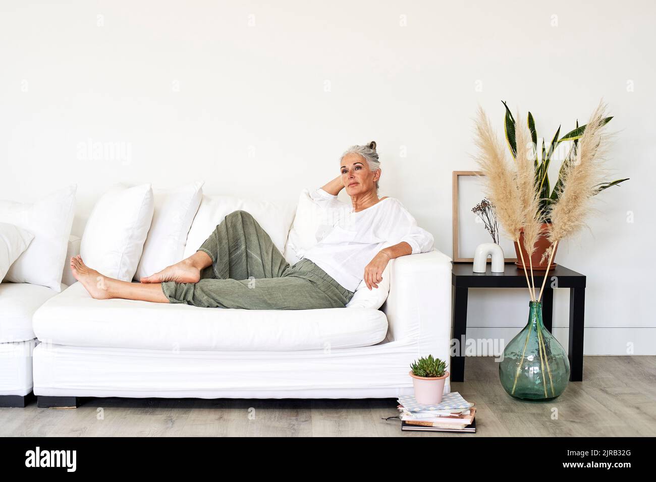 Mature woman relaxing on sofa at home Stock Photo - Alamy