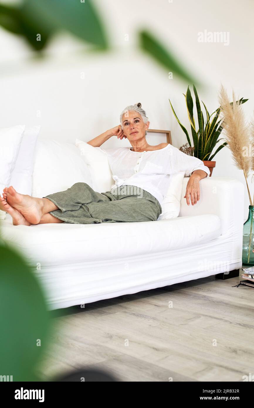 Thoughtful mature woman sitting on couch at home Stock Photo - Alamy