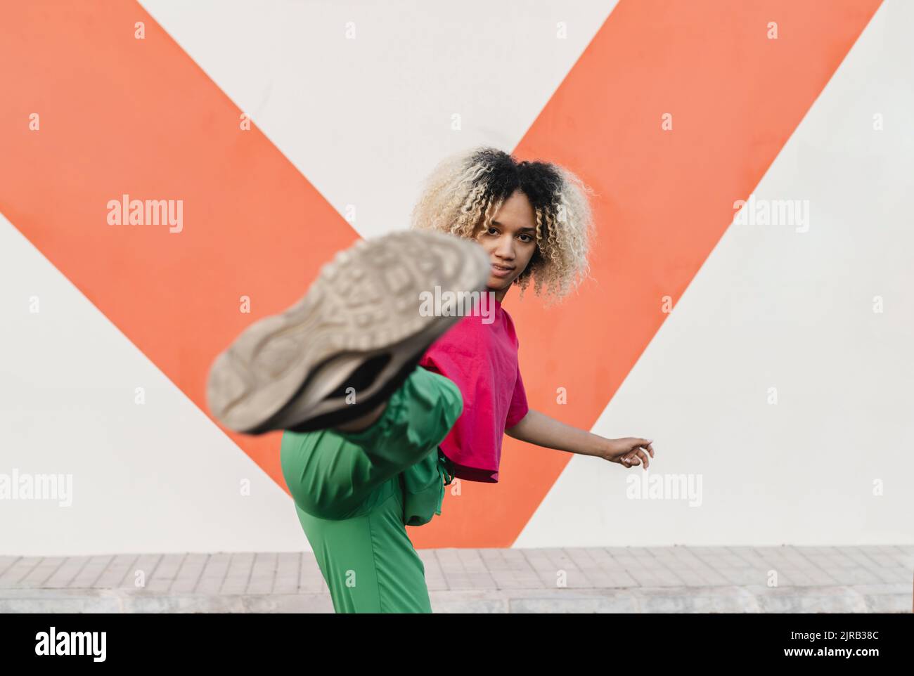 Young woman kicking in front of wall Stock Photo Alamy