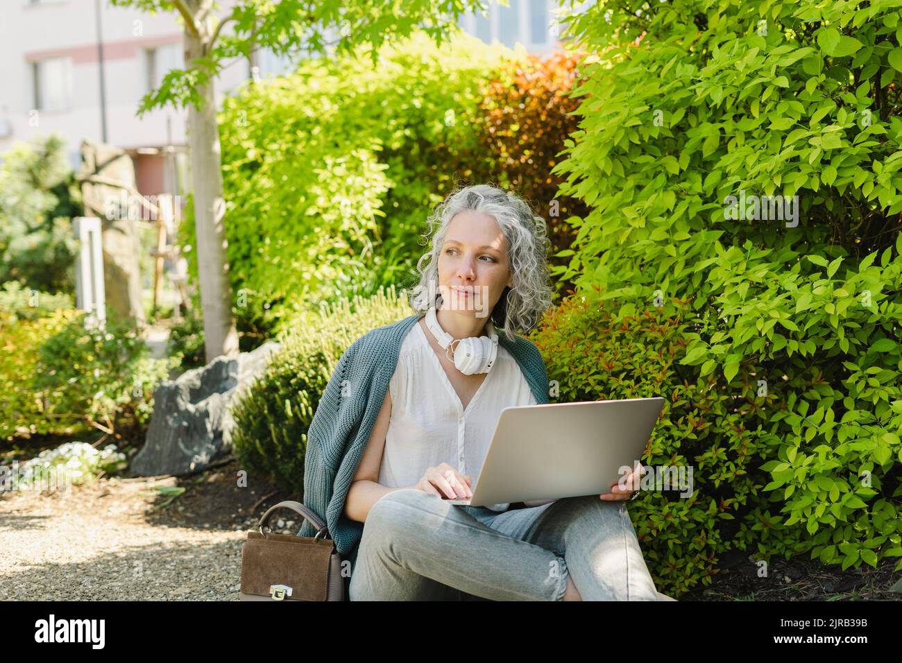 Thoughtful freelancer sitting with laptop in park Stock Photo