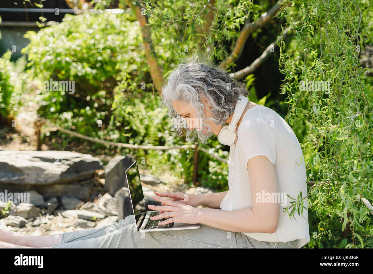 Freelancer using laptop by plants in park Stock Photo